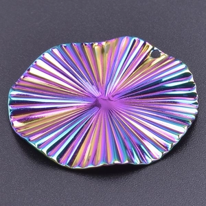 Macro shot of circular iridescent stainless steel pendant with radial pleat texture