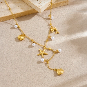 Golden Y-shaped stainless steel necklace with ocean charms and pearls on a stone