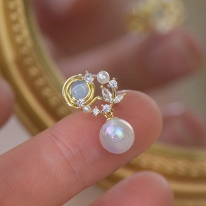 Macro shot of gold cat-eye earrings featuring zircon inlay and iridescent pearl drops