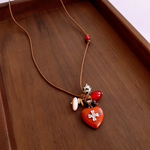 Gros plan d'un pendentif cœur ethnique avec perles en bois et détails de coquillages polis