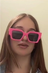 Detail view of pink square oversized sunglasses with dark lenses on a female model