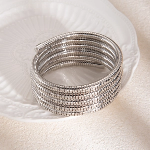 Gros plan d'un bracelet multi-rangs en chaîne serpent argentée sur un plateau blanc