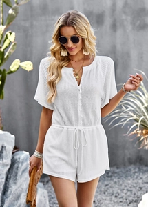 Close-up of white short-sleeve textured romper featuring V-neck buttons and elastic waist