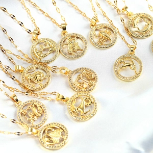 Detailed view of gold zodiac necklaces with micro-pave crystals on white satin