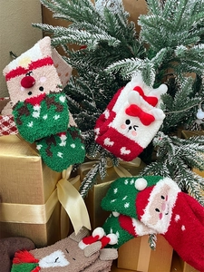 Close-up of fluffy coral fleece Christmas socks with festive cartoon elk and tree patterns