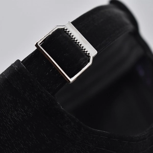 Macro shot of a black baseball cap featuring a premium silver metal adjustment buckle detail