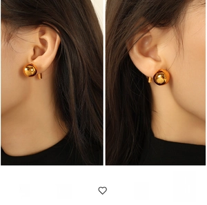 Detailed close-up of large oversized mirror-polished gold sphere earrings worn by a model