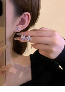 Macro shot of silver-colored flower stud earring with zirconia petals on model