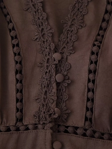 Dettaglio del pizzo, design traforato e bottoni rivestiti in tessuto sull'abito con scollo a V