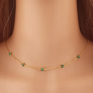 Macro view of dainty gold necklace featuring five small green clover leaf pendants