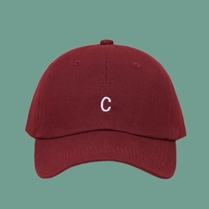 Close-up of white embroidered letter C on a deep red canvas baseball cap with fine texture
