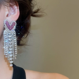 Detail of silver drop earrings featuring long rhinestone tassels and pink heart crystals