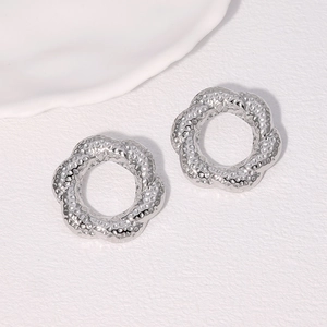 Macro shot of silver twisted hoop earrings with textured hammered finish on white background