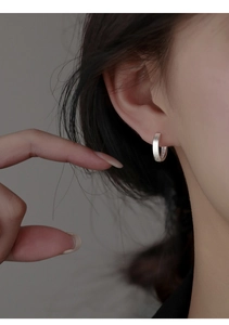 Macro detail of silver S925 hallmark on a minimalist brushed texture hoop earring