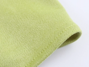 Makro-Detail der grünen Wildlederimitat-Stoffstruktur und hochwertigen Nähte am Kleid