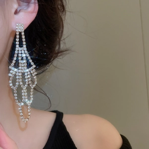 Macro detail of long silver tassel earrings with sparkling rhinestones for luxury evening wear