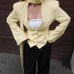 Detailed close-up of light yellow blazer with matching necktie and three-button closure
