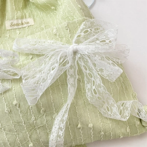 Detail of light green drawstring backpack with floral embroidery and lace bows