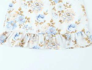 Nahaufnahme des Kleidersaums mit Blumenmuster und Rüschendetails aus leichtem Chiffon