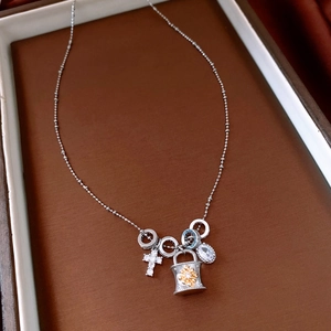 Dettaglio della collana con croce in argento, zircone bianco e lucchetto in un portagioie