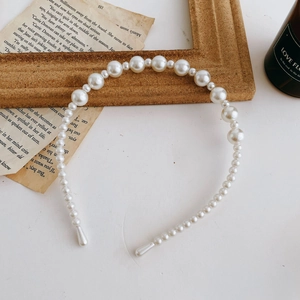 Detail of elegant pearl headband featuring alternating sizes of glossy white pearls