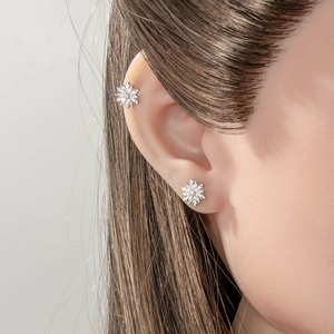Sparkling snowflake stud earrings with zircon stones worn on the earlobe and cartilage
