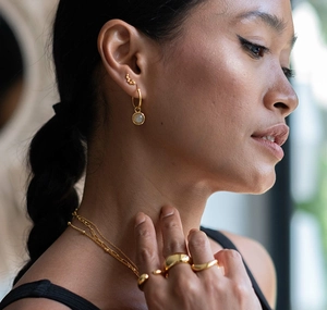 Close-up of a model wearing minimalist gold star earrings with a layering necklace