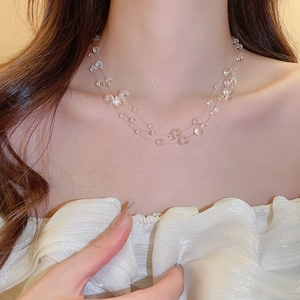Macro detail of triple-layer necklace with transparent crystal beads on model neck