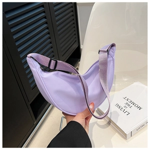 Detail of lavender nylon crescent bag with adjustable strap in a lifestyle setting