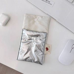 Detail of silver quilted pouch with butterfly pattern, snap closure and soft lining