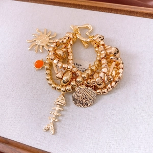 Detail of vintage gold layered bracelet with sun, fishbone, shell charms and OT clasp