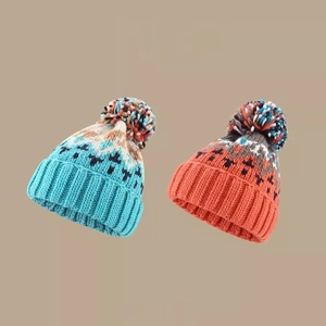 Blue and orange knit beanies with colorful pom poms and winter patterns on beige background