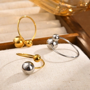 Macro shot of minimalist gold and silver bead rings on a textured jewelry display tray