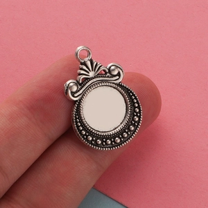 Close-up of 12mm antique silver scale pendant tray on a finger for size demonstration