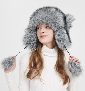 Detailed texture of thick faux fox fur winter hat with large plush pom-poms for warmth