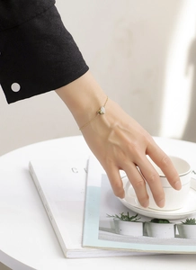 Detailed view of an elegant heart-shaped zircon bracelet on a wrist in a tea setting