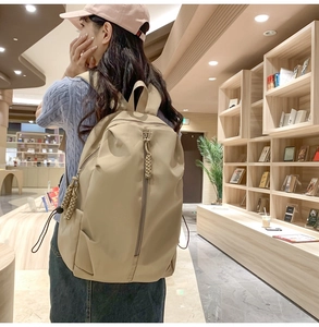 Beige large capacity backpack shown in a library setting with wide padded shoulder straps