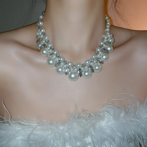 Detailed close-up of layered faux pearl and rhinestone bib necklace on a model's neck