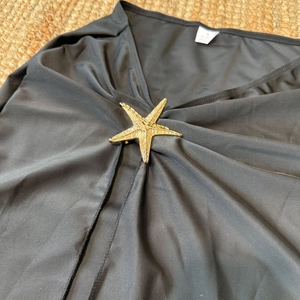 Détail du bikini noir avec accessoire étoile de mer dorée et étiquette taille S