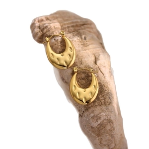 Golden stainless steel U-shaped hoop earrings with radial texture on a stone base