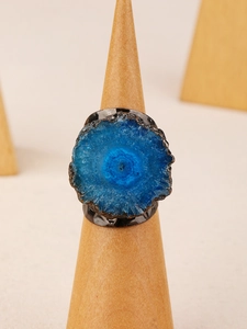 Macro detail of a blue druzy agate stone set on a textured black metal adjustable ring