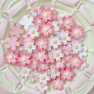 Macro detail of pink and white gradient resin cherry blossom charms on a beige plate