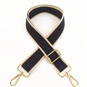 Detail of adjustable woven strap with maze pattern and golden metal swivel snap hooks