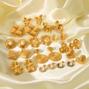 Various 18K gold-plated stainless steel earrings displayed on elegant beige silk fabric