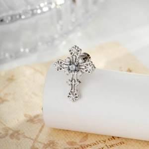 Silver lava cross earring with dark grey gem and clear zircon stones on a paper backdrop