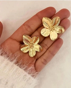 Detailed close-up of golden flower stud earrings with a brushed metallic texture finish