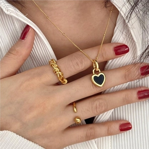 Close-up of gold knotted rings and heart necklace on model with striped shirt