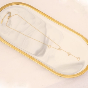 Detail of golden butterfly necklace with white charms on a luxury marble tray