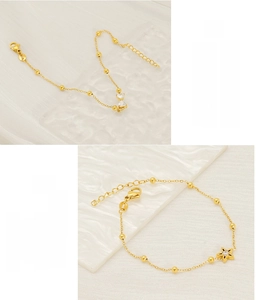 Detail of two gold plated stainless steel bead bracelets with bow and star charms