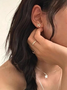 Detail shot of golden hammered flower earrings and matching necklace set on a model